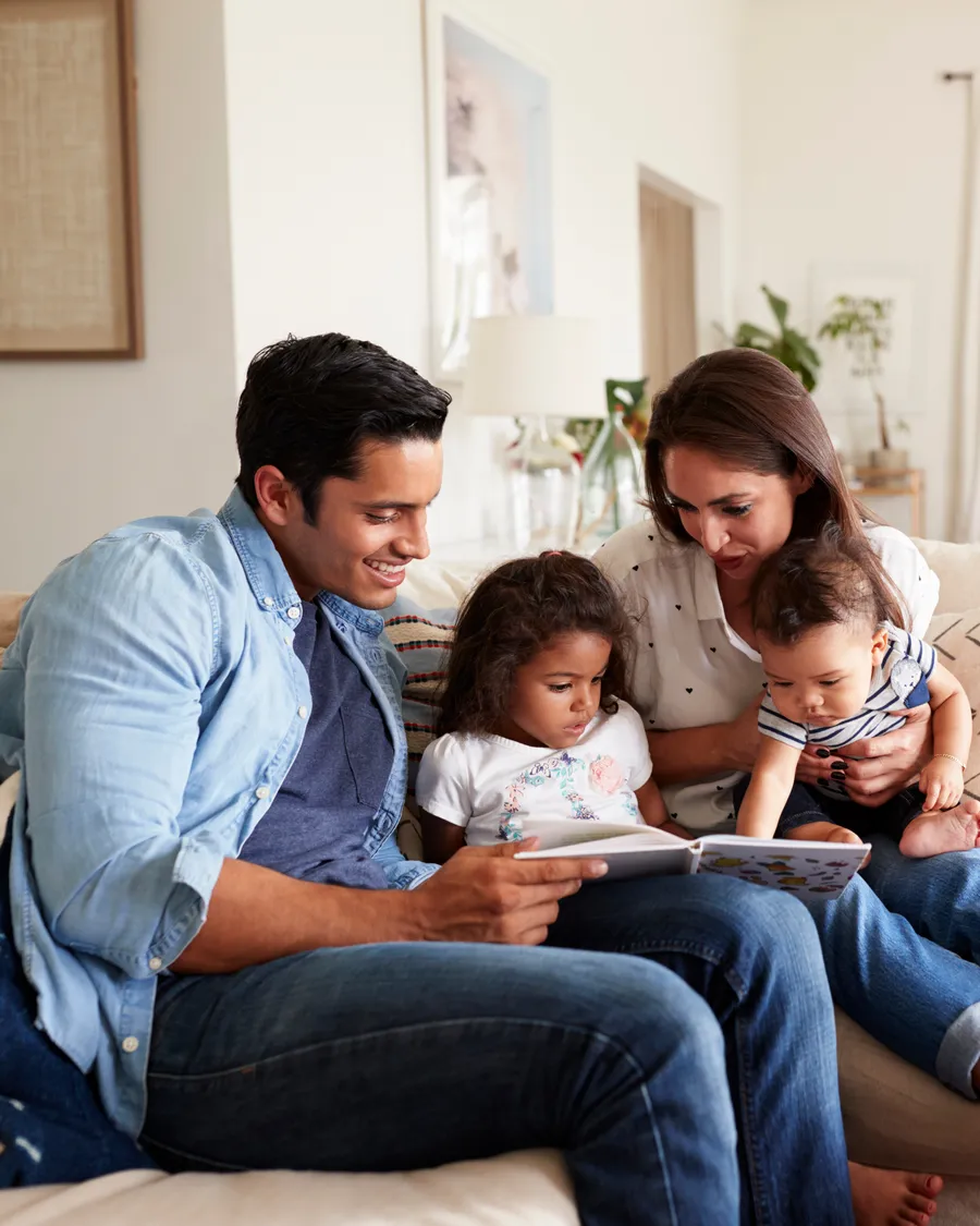 Familia latina leyendo junta en casa, ambiente cálido y aspiracional