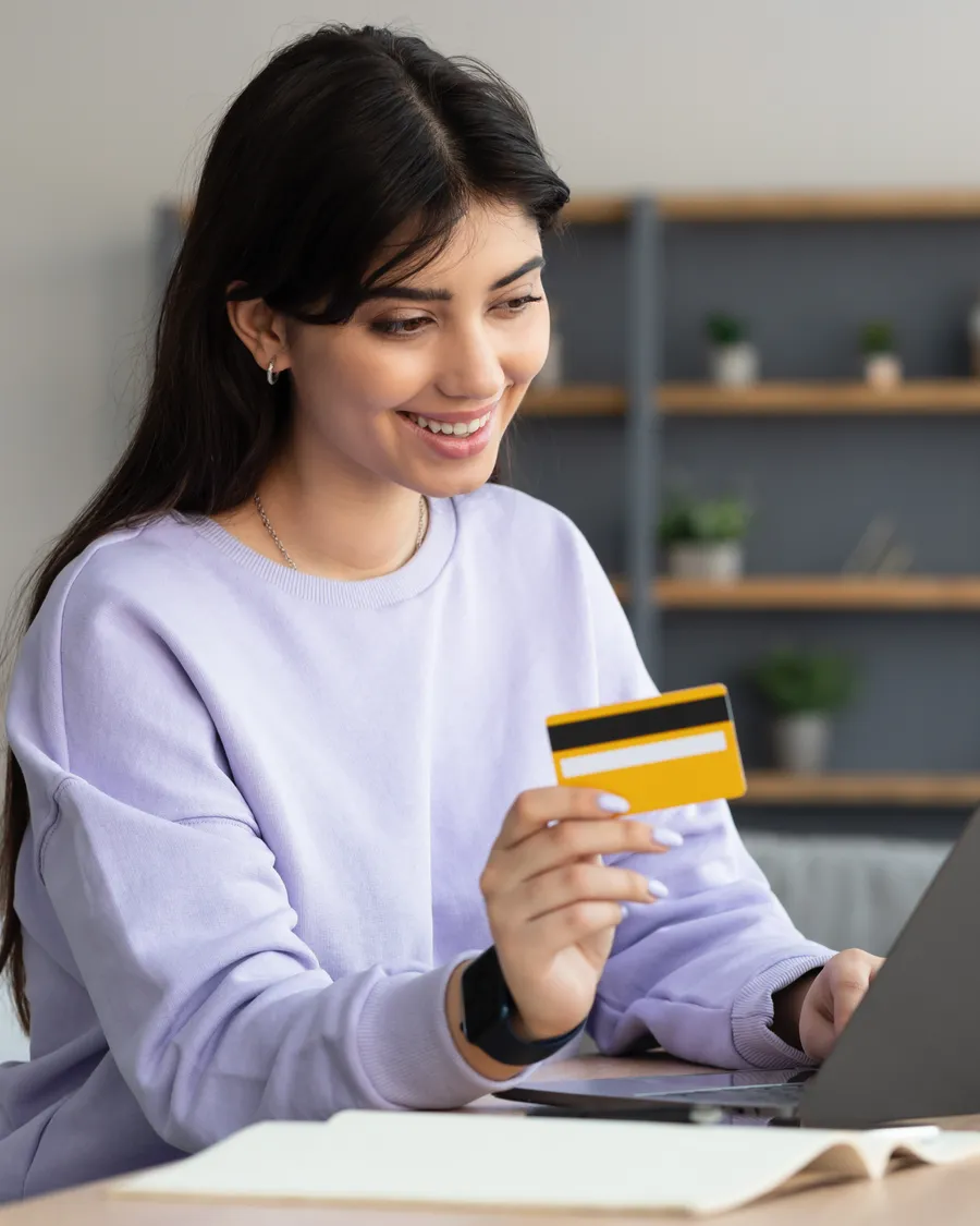 Persona gestionando su crédito con tarjeta y computadora en casa